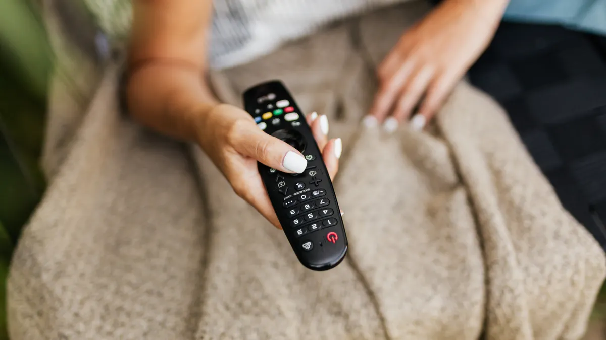 Fjernkontroll i sofaen, der Bluetooth-kontrollen virker uten fri sikt til TV-boksen