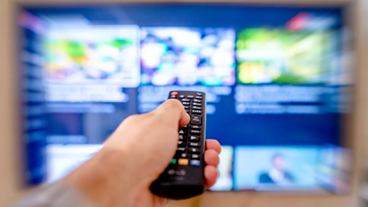 Hånd med fjernkontroll som styrer Android TV-menyen